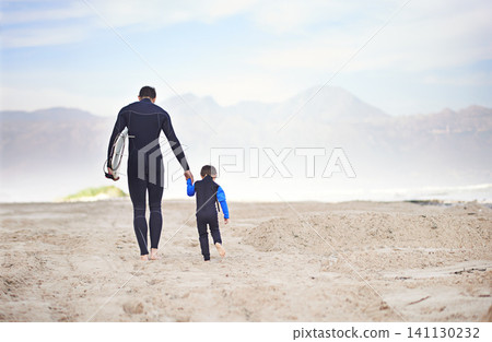 Surfboard, man and child on beach, walking and holding hands on outdoor bonding adventure. Nature, father and son at ocean for surfing, teaching and learning together with support, trust and growth. Surfboard, man and child on beach, walking and holding hands on outdoor bonding adventure. Nature, father and son at ocean for surfing, teaching and learning together with support, trust and growth. 141130232