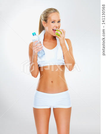 Woman, portrait and apple or water for eating in studio with smile, healthy diet or nutrition for wellness goal. Athlete, person and happy with fruit to lose weight or body detox on white background Woman, portrait and apple or water for eating in studio with smile, healthy diet or nutrition for wellness goal. Athlete, person and happy with fruit to lose weight or body detox on white background 141130568