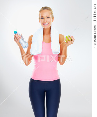 Woman, portrait and apple or water for wellness in studio with smile, healthy diet or nutrition for fitness goal. Athlete, person and happy with fruit to lose weight or body detox on white background 141130584