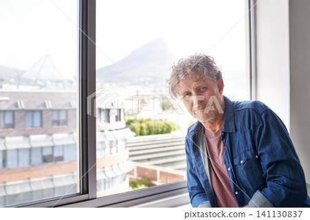 Man, smile and portrait with window in city for relax with view and building for urban and break in house. Mature person and leaning for comfort indoor for peace and alone with mountain and sun flare 141130837