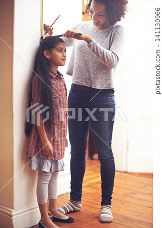 Mother, child and measuring tape for height with ruler at wall for growth development in home, childhood or bonding. Female person, daughter and pencil in apartment for size checking, youth or parent Mother, child and measuring tape for height with ruler at wall for growth development in home, childhood or bonding. Female person, daughter and pencil in apartment for size checking, youth or parent 141130966