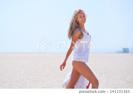 Portrait, smile and beach with woman, vacation and getaway trip with sunshine and adventure. Person, outdoor and seaside with sand and summer with holiday and travelling with blue sky, joy and ocean 141131163
