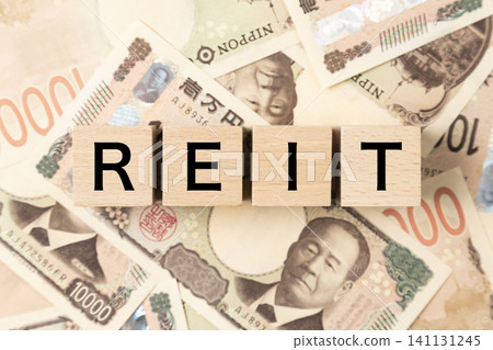 一塊寫著「REIT」字樣的磚塊和許多1萬日圓面額的鈔票 一塊寫著「REIT」字樣的磚塊和許多1萬日圓面額的鈔票 141131245