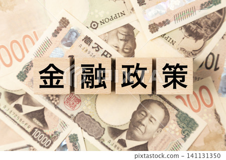 一塊寫著「貨幣政策」字樣的磚塊，以及許多面額為10,000日圓的鈔票。 141131350