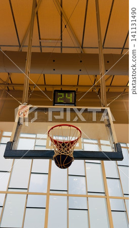 Game-winning point: Basketball in net with '24' second shot clock and warning sign, modern sports complex 141131490