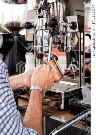 Barista Steaming Milk with Professional Equipment 141131574