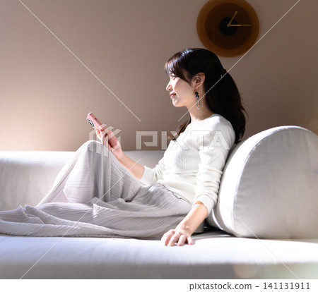 觀看在沙發的婦女一個智能手機 141131911