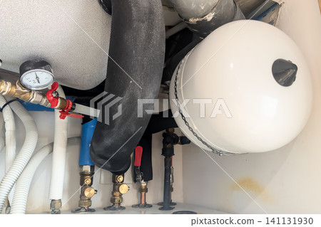 Close view of a new white expansion vessel a pressure gauge and brass fittings. Detail of a repaired hot water system Close view of a new white expansion vessel a pressure gauge and brass fittings. Detail of a repaired hot water system 141131930