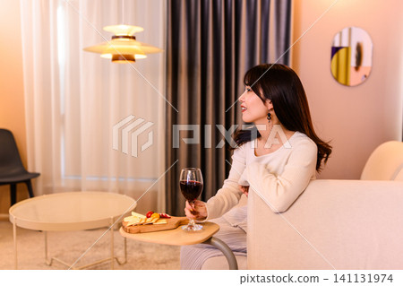 A woman relaxing with a glass of wine in her hand. A woman relaxing with a glass of wine in her hand. 141131974