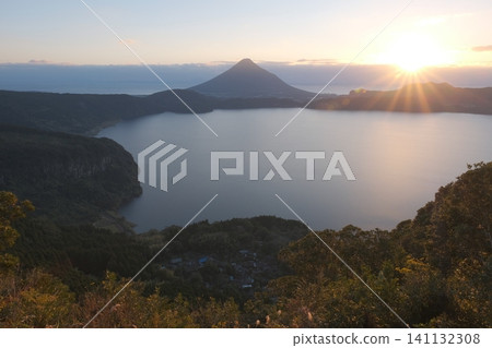 A bird's-eye view of the Ikeda Lake caldera and Mount Kaimon, with the brilliant rays of the setting sun spreading beautifully across the landscape. A bird's-eye view of the Ikeda Lake caldera and Mount Kaimon, with the brilliant rays of the setting sun spreading beautifully across the landscape. 141132308