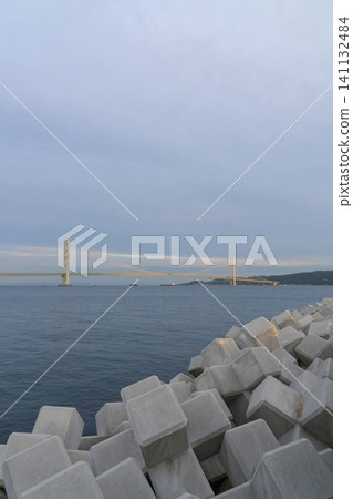The Akashi Kaikyo Bridge and the calm sea as seen from the coast. The Akashi Kaikyo Bridge and the calm sea as seen from the coast. 141132484