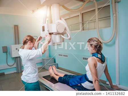Radiologist and patient in a x-ray room. Classic ceiling-mounted x-ray system. Radiologist and patient in a x-ray room. Classic ceiling-mounted x-ray system. 141132682