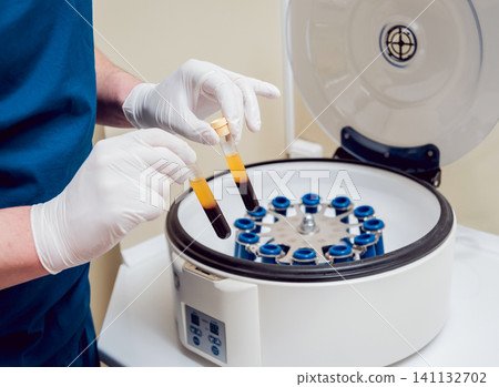 Platelet-Rich plasma preparation. Tube with blood in hands. Centrifuge. Platelet-Rich plasma preparation. Tube with blood in hands. Centrifuge. 141132702