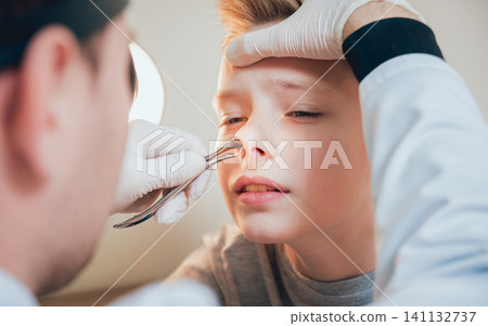Otolaryngologist examines boy nose with nasolar dilatator. Otolaryngologist examines boy nose with nasolar dilatator. 141132737