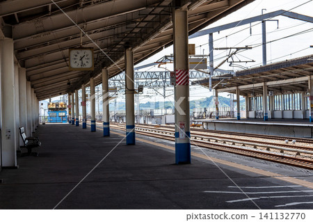 A quiet, deserted train station platform and clock. A quiet, deserted train station platform and clock. 141132770