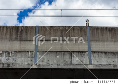 A concrete railway viaduct's sound barrier, viewed against a blue sky. 141132771