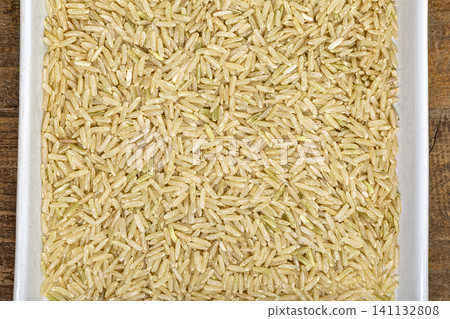 Hom Mali brown rice and white rice grains close-up in a bowl, showing natural color variation and long kernels of jasmine rice for food, cooking, and nutrition concepts Hom Mali brown rice and white rice grains close-up in a bowl, showing natural color variation and long kernels of jasmine rice for food, cooking, and nutrition concepts 141132808