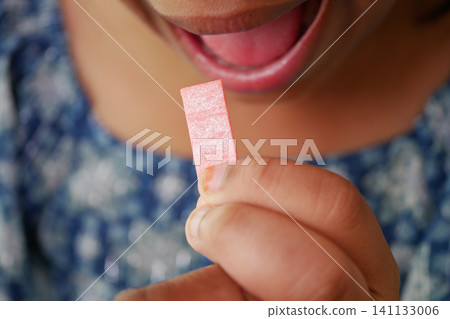 A child holding a pink stick of bubble gum A child holding a pink stick of bubble gum 141133006