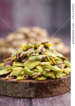 Close-Up Pile of Sliced Shelled Pistachios on Rustic Wooden Board for Baking and Garnish 141133091