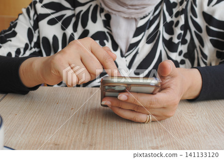 Engaging with a smartphone in a cozy cafe setting Engaging with a smartphone in a cozy cafe setting 141133120