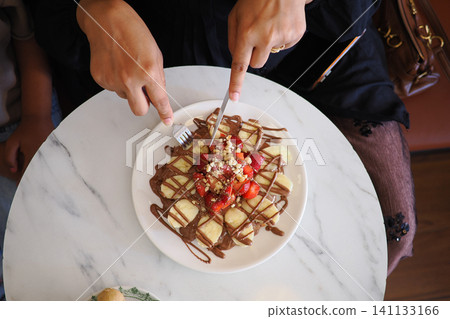 Turkish style waffle topped with strawberries, bananas, and a chocolate drizzle Turkish style waffle topped with strawberries, bananas, and a chocolate drizzle 141133166