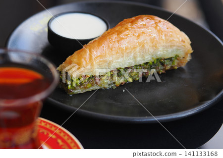 Delicious baklava slice served with creamy dip and tea Delicious baklava slice served with creamy dip and tea 141133168