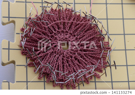 Hands shaping a crochet decorative piece during blocking 141133274