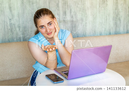 Young woman with laptop offering a hand while working online at home and smiling at camera Young woman with laptop offering a hand while working online at home and smiling at camera 141133612