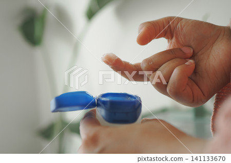 Applying lotion from a blue container in a home setting Applying lotion from a blue container in a home setting 141133670