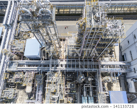 High-angle drone shot of complex pipelines and steel structures in a massive petrochemical plant and industrial complex. High-angle drone shot of complex pipelines and steel structures in a massive petrochemical plant and industrial complex. 141133728