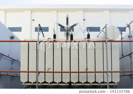 A large power transformer with cooling fins and ceramic insulators at an electrical substation A large power transformer with cooling fins and ceramic insulators at an electrical substation 141133786