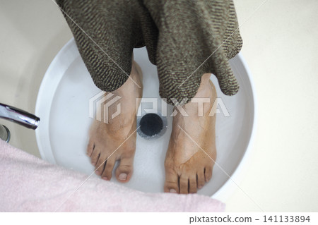 Feet in water with towel nearby during relaxation time Feet in water with towel nearby during relaxation time 141133894