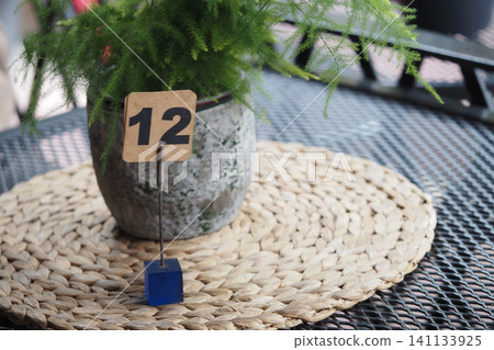 Table number 12 with plant in a pot on a woven mat Table number 12 with plant in a pot on a woven mat 141133925