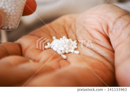 Hand Holding Small White Homeopathy Pellets Medicine in Palm Closeup Alternative Remedy Dose Hand Holding Small White Homeopathy Pellets Medicine in Palm Closeup Alternative Remedy Dose 141133963