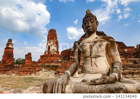 A statue of a Buddha is sitting in front of a large building A statue of a Buddha is sitting in front of a large building 141134049
