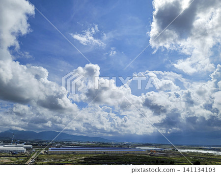 A blue sky with clouds and a large building in the background A blue sky with clouds and a large building in the background 141134103