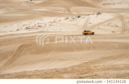 An off-road jeep driving across the vast sand dunes of Mui Ne, Vietnam. An off-road jeep driving across the vast sand dunes of Mui Ne, Vietnam. 141134128