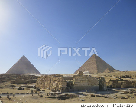 The majestic Great Pyramids of Giza standing under a clear blue sky in Cairo, Egypt, featuring ancient limestone structures. The majestic Great Pyramids of Giza standing under a clear blue sky in Cairo, Egypt, featuring ancient limestone structures. 141134129