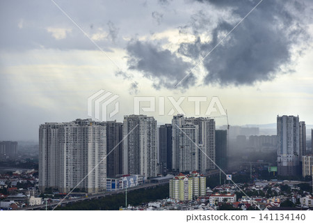 High-rise apartment buildings under dark storm clouds and a passing rain shower in the city High-rise apartment buildings under dark storm clouds and a passing rain shower in the city 141134140