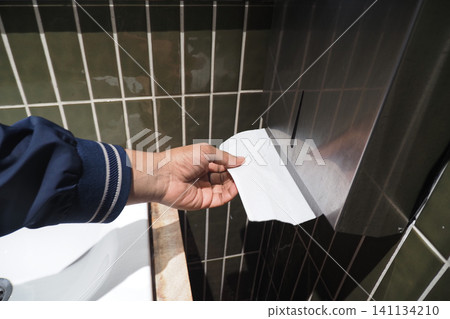 Hand reaches for paper towel in public restroom Hand reaches for paper towel in public restroom 141134210