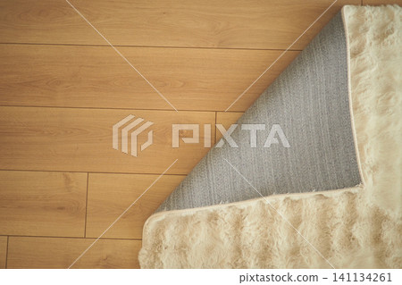 Cozy rug partially rolled up on wooden floor in a home Cozy rug partially rolled up on wooden floor in a home 141134261