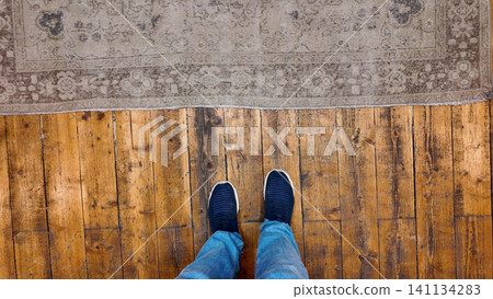 Footwear on wooden floor next to decorative rug 141134283