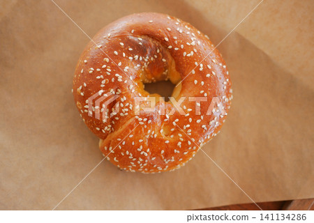 Freshly baked sesame bagel on parchment paper Freshly baked sesame bagel on parchment paper 141134286