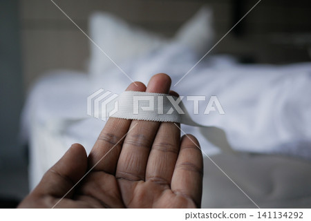 Hand holding white ribbon in a softly lit room Hand holding white ribbon in a softly lit room 141134292