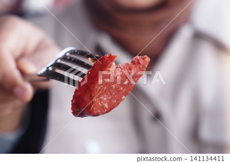 Deliciously prepared sausage on a fork during a meal Deliciously prepared sausage on a fork during a meal 141134411