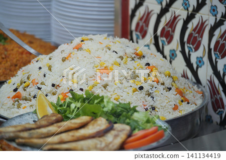 Rice dish with grilled fish on a silver platter at a market Rice dish with grilled fish on a silver platter at a market 141134419