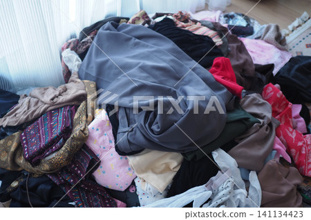 Clothes piled on the floor in a room Clothes piled on the floor in a room 141134423