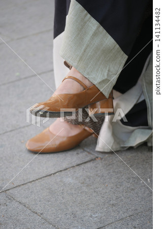 Stylish brown high-heel shoes on a city sidewalk Stylish brown high-heel shoes on a city sidewalk 141134482