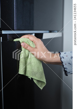 Cleaning the surface of a refrigerator with a cloth 141134655