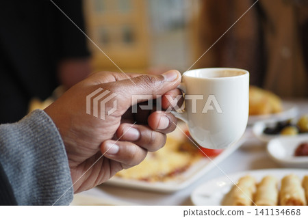 Holding a turkish coffee at a food gathering in a bright space Holding a turkish coffee at a food gathering in a bright space 141134668